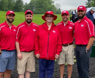 5 men standing together wearing red smiling