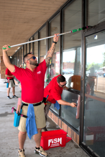 three window cleaners cleaning windows of a building