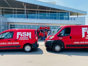 two red fish window cleaning vans and fish team standing in front of the performing arts center