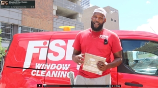 Window cleaner standing in front of red Fish Window Cleaning van holding a book