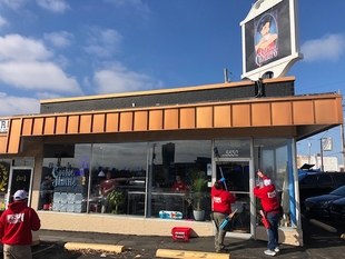 three window cleaners cleaning windows of a small building