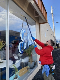 window cleaner cleaning windows of a small coffee shop