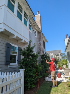 window cleaner cleaning windows of a house with a pole
