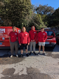 four fish employees standing in front of a red fish window cleaning van and a red fish window cleaning car