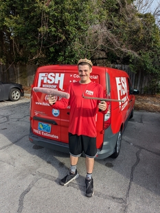 window cleaner holding two squeegees in front of a red fish window cleaning van