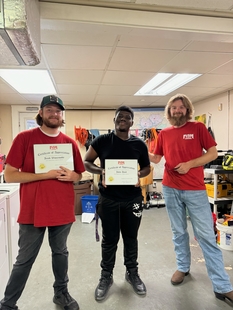 three fish employees posing with two awards