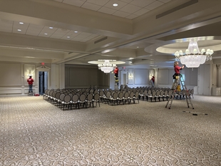 three window cleaners cleaning lights and chandeliers of a building
