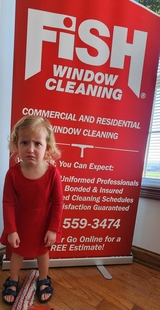 little girl looking upset in front of a fish window cleaning sign