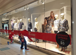 window cleaners cleaning display case windows at a mall
