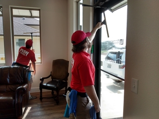 two window cleaners cleaning interior windows and glass doors of a building