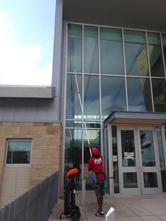 window cleaner cleaning windows of a building with a pole