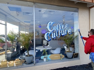 window cleaner cleaning windows of a small coffee shop