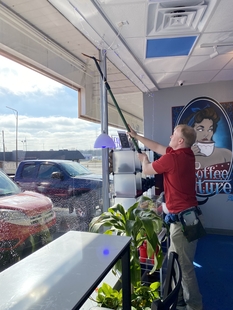 window cleaner cleaning windows of a small coffee shop