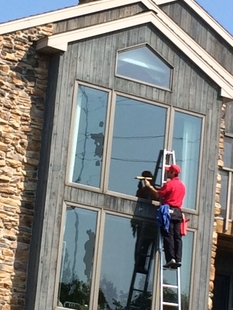 window cleaner cleaning window of a house on a ladder