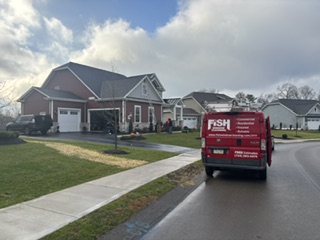 Red Fish Window Cleaning van parked on a roadway in front of a residential home