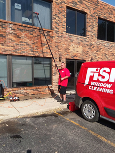 Image of Fish Window Cleaner Cleaning Window with Water-Fed Pole Next to Branded Van