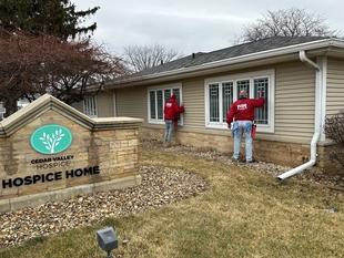 two window cleaners cleaning windows of a hospice home