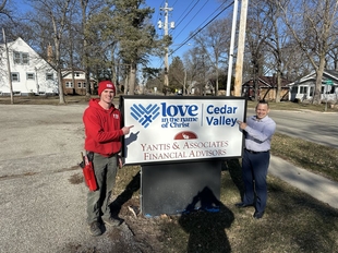 window cleaner standing with woman and pointing at cedar valley gearheads ministries sign