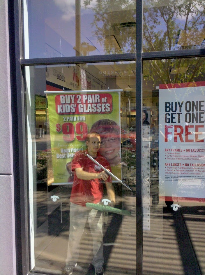 Image of Window Cleaner Cleaning Storefront Windows with Squeegee