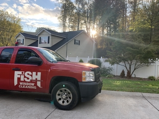 Front End of Branded Truck with Sun Shining Through House and Trees
