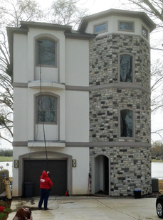 window cleaner cleaning windows of a tall house wiht long pole