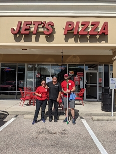 two fish employees standing in front of jet's pizza with employee at jet's pizza