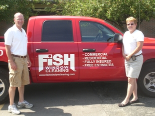 owners joe and bridget lang standing in front of red fish window cleaning truck