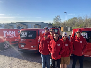 some fish employees standing infront of four red fish window cleaning vans