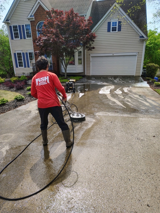 window cleaner pressure washing the driveway of a house