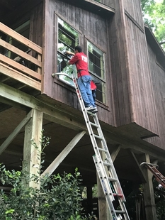 window cleaner cleaning window of a house while on a ladder