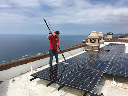 Person is red Fish Window Cleaning shirt using a waterfed pole to clean solar panels