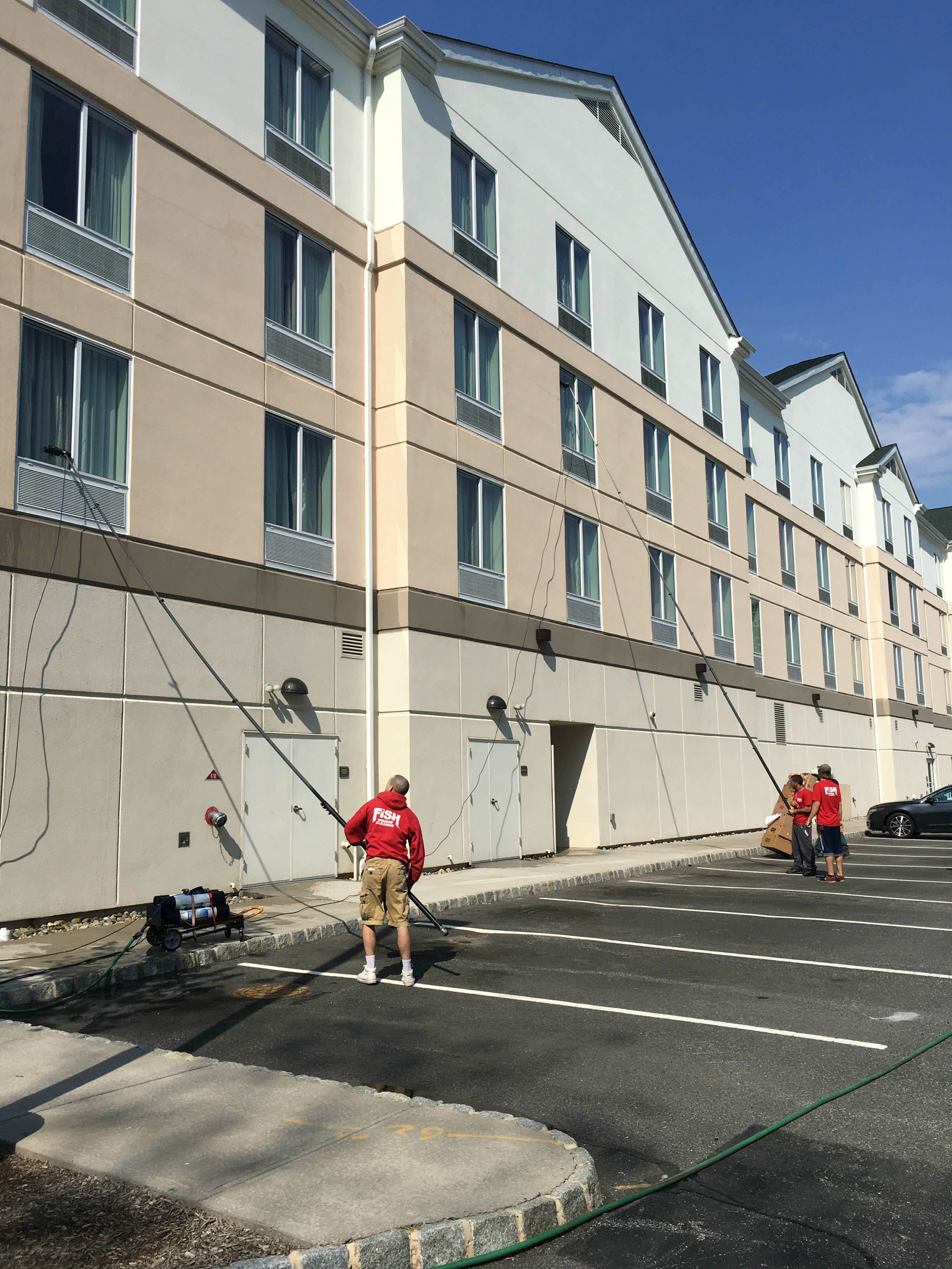 Two Window Cleaners Using Poles to Clean 2nd Story Windows