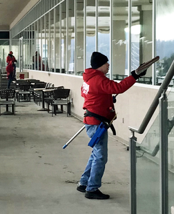 FISH Window Cleaner Adjusts Mop on Pole in Front of Storefront Windows