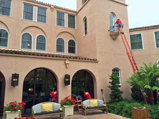 Fish Window Cleaners Use a Ladder to Clean Windows on Large Spanish-Style Home