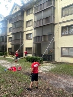 Two Window Cleaners Using Water-Fed Poles to Clean 4-Story Apartment Building