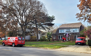 Two Branded Vans in Front of 2-Story House with Two Fish Window Cleaners on Porch