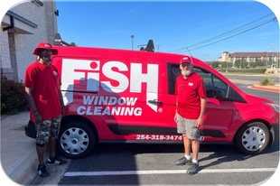 two fish employees in front of a red fish van