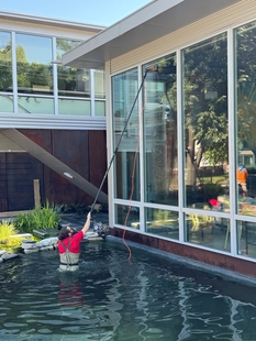 window cleaner cleaning tall windows of a house while standing in a pool